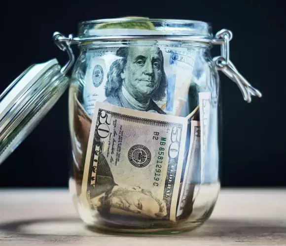 Glass jar filled with US dollar bills